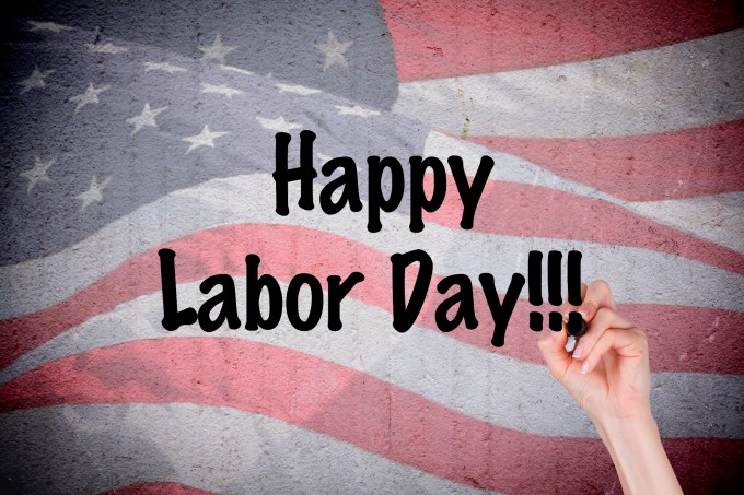 Hand writing Happy Labor Day on grunge wall with American flag